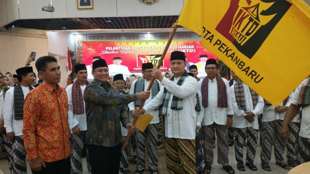 Ketum IKTD Riau, Eddy Tanjung menyerahkan bendera pataka kepada Ketu IKTD Pekanbaru, Taufik Arrakhman. (istimewa)